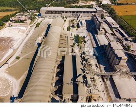 Industrial facility located in a rural area surrounded by fields and trees showing large structures and machinery Industrial facility located in a rural area surrounded by fields and trees showing large structures and machinery 141444942