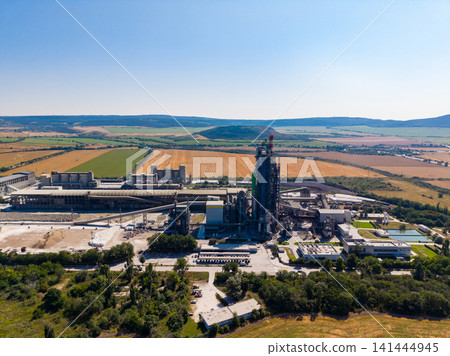 Industrial facility near fields and mountains in a clear blue sky during daytime hours 141444945