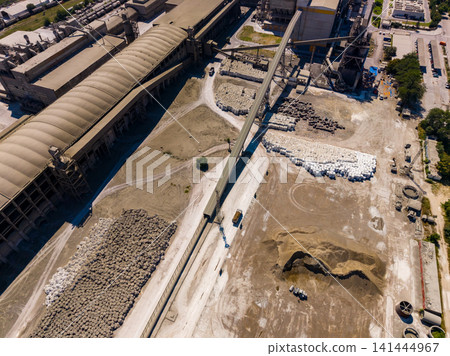 Construction site shows machinery and materials in action on a sunny day in an industrial area with various piles and structures visible Construction site shows machinery and materials in action on a sunny day in an industrial area with various piles and structures visible 141444967