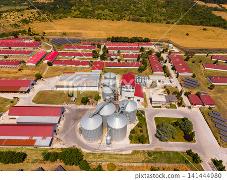 Farm complex with grain silos and storage buildings seen from above in rural area during daytime 141444980