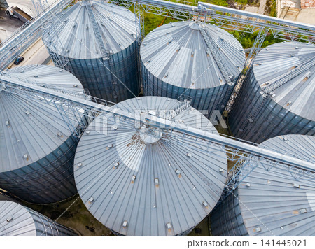 Rows of large metal silos used for grain storage in an agricultural area during daylight Rows of large metal silos used for grain storage in an agricultural area during daylight 141445021