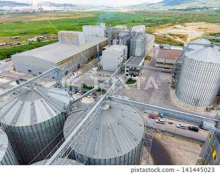View of a grain storage facility and processing plant in a rural area with silos and large buildings during daytime View of a grain storage facility and processing plant in a rural area with silos and large buildings during daytime 141445023