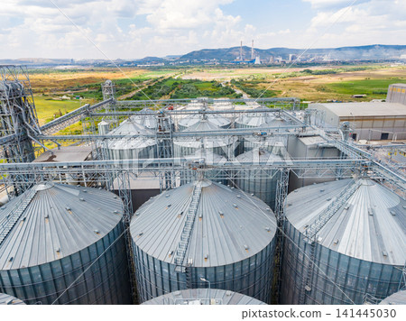 View of large silos in a farming area near a power plant with open fields and distant mountains View of large silos in a farming area near a power plant with open fields and distant mountains 141445030