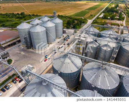 View of grain silos at an agricultural site with fields in the background during daytime View of grain silos at an agricultural site with fields in the background during daytime 141445031