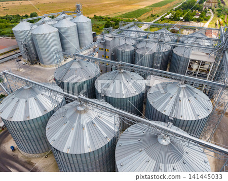 Grain storage facility with silos and machinery in a rural area during daytime Grain storage facility with silos and machinery in a rural area during daytime 141445033