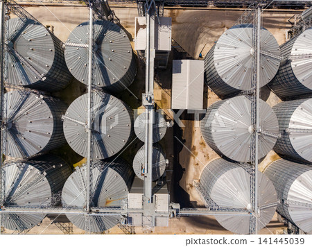 Large storage facility with metal silos in a rural area showing the layout from above during daylight Large storage facility with metal silos in a rural area showing the layout from above during daylight 141445039