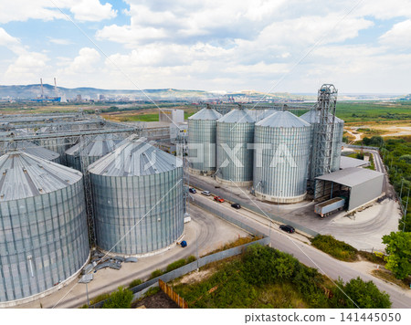 Large grain storage facility located outside a city with silos and trucks visible on a clear day Large grain storage facility located outside a city with silos and trucks visible on a clear day 141445050
