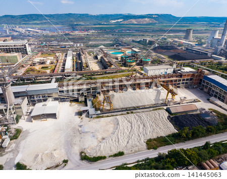 Industrial site with large buildings, machinery, storage areas, and processing facilities in a wide landscape during daylight hours Industrial site with large buildings, machinery, storage areas, and processing facilities in a wide landscape during daylight hours 141445063