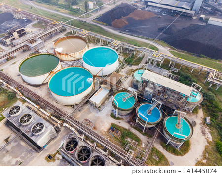 Industrial water treatment facility with large circular tanks and processing equipment in the background on a clear day Industrial water treatment facility with large circular tanks and processing equipment in the background on a clear day 141445074