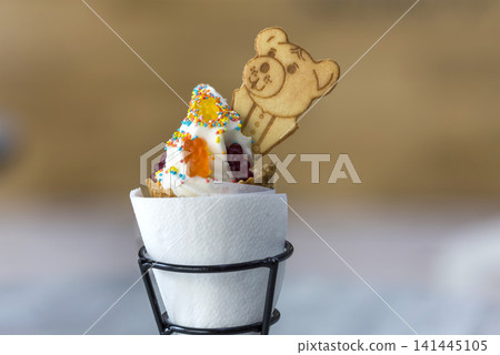 Ice cream cone dessert with cookies creative decoration topping on blurred light copy space background. Ice cream cone dessert with cookies creative decoration topping on blurred light copy space background. 141445105