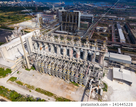 Large industrial plant located near the coast with various structures and pipes visible in the clear sky during daytime Large industrial plant located near the coast with various structures and pipes visible in the clear sky during daytime 141445228