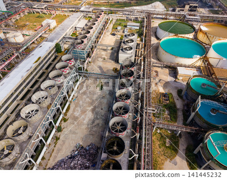 Industrial site with large tanks and cooling fans located in an urban area under clear skies during daytime Industrial site with large tanks and cooling fans located in an urban area under clear skies during daytime 141445232