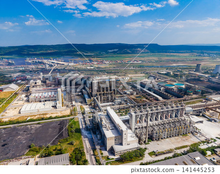 View of industrial area with factories, storage silos, roads, and river nearby during daytime 141445253