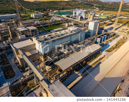 Industry site with factories and machinery in a rural area during the day with smoke rising from stacks Industry site with factories and machinery in a rural area during the day with smoke rising from stacks 141445286