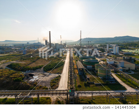 Industrial area with factories and pipes under a clear sky in the afternoon Industrial area with factories and pipes under a clear sky in the afternoon 141445304
