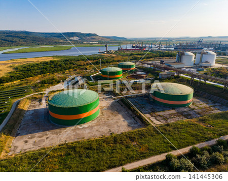 Storage tanks located near a river with industry in the background during the day Storage tanks located near a river with industry in the background during the day 141445306