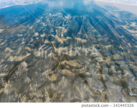 Water and sand blend at the beach during low tide creating patterns and reflections under bright sunlight Water and sand blend at the beach during low tide creating patterns and reflections under bright sunlight 141445326