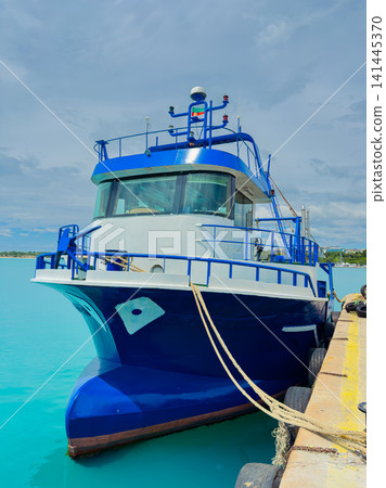 Boat docks at the pier with clear blue water and a cloudy sky during the day in a coastal area Boat docks at the pier with clear blue water and a cloudy sky during the day in a coastal area 141445370