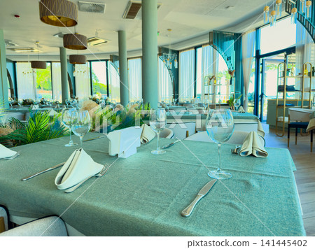 Dining setup at a restaurant with tables arranged neatly by the window during the daytime with natural light coming in Dining setup at a restaurant with tables arranged neatly by the window during the daytime with natural light coming in 141445402