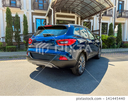 Car parked outside a building with trees, in bright sunlight on a clear day 141445440