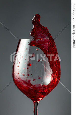 An image of red wine being splashed into a glass. 141445799