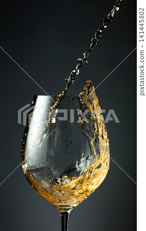 An image of white wine being splashed into a glass. 141445802