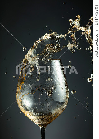 An image of white wine being splashed into a glass. 141445803