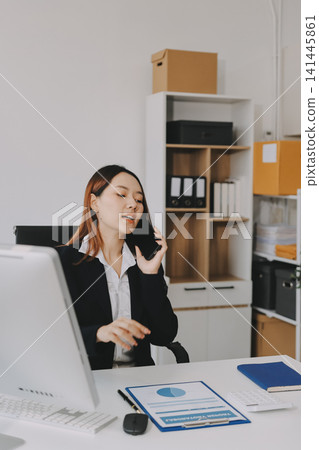 Asian businesswoman using calculator and working on laptop at modern office Asian businesswoman using calculator and working on laptop at modern office 141445861
