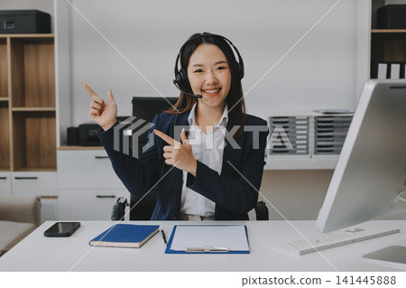 Smiling Asian Woman Telemarketing Agent with Headset Working at Smiling Asian Woman Telemarketing Agent with Headset Working at 141445888