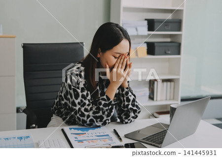 Tried young Asian office employee feeling sick and have a headache from a long working day at office Tried young Asian office employee feeling sick and have a headache from a long working day at office 141445931