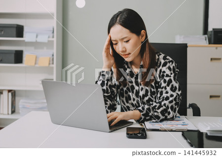 Tried young Asian office employee feeling sick and have a headache from a long working day at office Tried young Asian office employee feeling sick and have a headache from a long working day at office 141445932