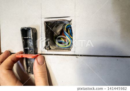 Professional tiler installing ceramic wall tiles with a leveling system to ensure perfectly even surfaces and clean grout lines during a home renovation project 141445982