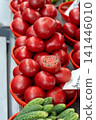 Ripe red tomatoes on a market stall. Tomatoes for sale at a market. A cut tomato reveals its ripe, juicy flesh and texture. 141446010