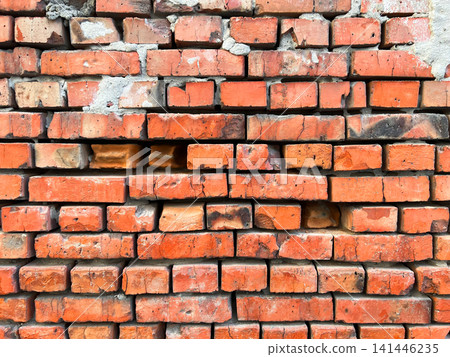 Weathered red brick wall with aged mortar joints showing cracks and wear in a close-up view Weathered red brick wall with aged mortar joints showing cracks and wear in a close-up view 141446235