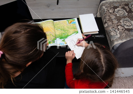 Young girl drawing and learning about geography with her mother at home, family time, education, creativity and bonding. Young girl drawing and learning about geography with her mother at home, family time, education, creativity and bonding. 141446545