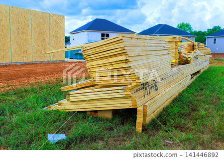 Wood beams planks are stacked neatly at construction site surrounded by homes be preparing for building. Wood beams planks are stacked neatly at construction site surrounded by homes be preparing for building. 141446892