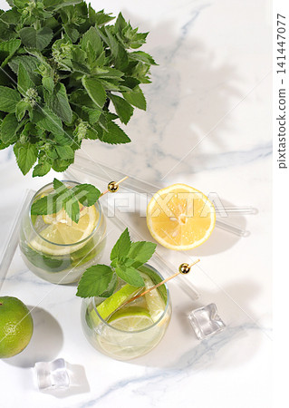 Icy homemade lemonade, juice or cocktail with mint, spearmint, lime, lemon and citrus, a refreshing summer drink recipe, a detox diet and weight loss concept, nonalcoholic mojito for energy Icy homemade lemonade, juice or cocktail with mint, spearmint, lime, lemon and citrus, a refreshing summer drink recipe, a detox diet and weight loss concept, nonalcoholic mojito for energy 141447077