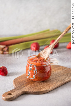 Homemade strawberry rhubarb jam in glass jar with wooden spoon 141447738