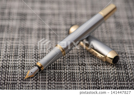 Fountain pen, beautiful fountain pen with details on a rustic surface with braided wires, selective focus. Fountain pen, beautiful fountain pen with details on a rustic surface with braided wires, selective focus. 141447827