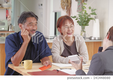 A middle-aged couple receiving an explanation about pension benefits. A middle-aged couple receiving an explanation about pension benefits. 141448080