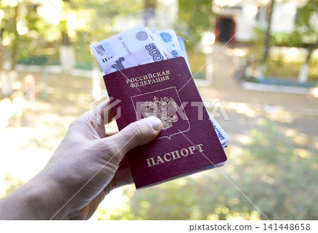 passport of a Russian citizen with invested rubles in a man's hand passport of a Russian citizen with invested rubles in a man's hand 141448658