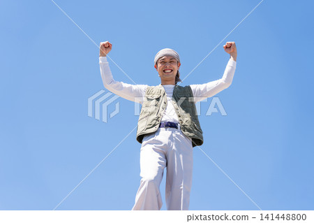 一名身穿工作服的男子在藍天下擺出勝利姿勢。 一名身穿工作服的男子在藍天下擺出勝利姿勢。 141448800