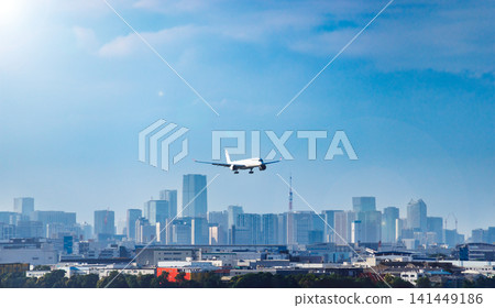 A passenger plane begins its descent for landing with Tokyo's waterfront cityscape as a backdrop. A passenger plane begins its descent for landing with Tokyo's waterfront cityscape as a backdrop. 141449186