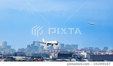 A passenger plane begins its descent for landing with Tokyo's waterfront cityscape as a backdrop. A passenger plane begins its descent for landing with Tokyo's waterfront cityscape as a backdrop. 141449187