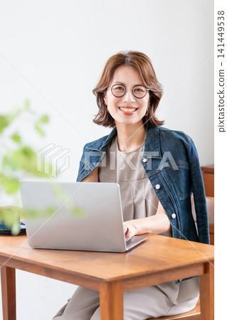 在客廳裡使用電腦的中年婦女 在客廳裡使用電腦的中年婦女 141449538