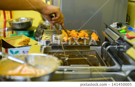 Chef preparing crispy fried chicken in a commercial kitchen with a deep fryer Chef preparing crispy fried chicken in a commercial kitchen with a deep fryer 141450005