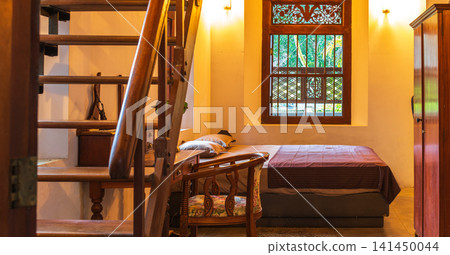 Cozy loft bedroom with wooden staircase and warm ambient lighting Cozy loft bedroom with wooden staircase and warm ambient lighting 141450044