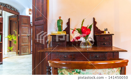 Vintage wooden dressing table with tropical flowers and a chair beside the door Vintage wooden dressing table with tropical flowers and a chair beside the door 141450050