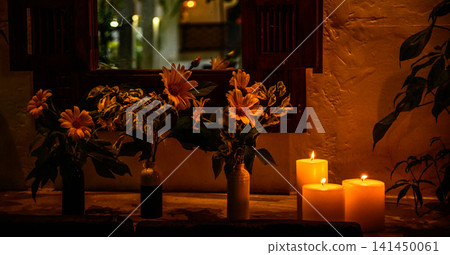 Cozy candlelit floral arrangement by rustic wooden window with warm ambient lighting Cozy candlelit floral arrangement by rustic wooden window with warm ambient lighting 141450061