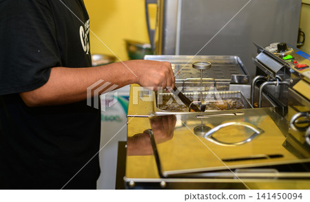 Chef deep-frying fried chicken in a commercial kitchen, close-up. Chef deep-frying fried chicken in a commercial kitchen, close-up. 141450094